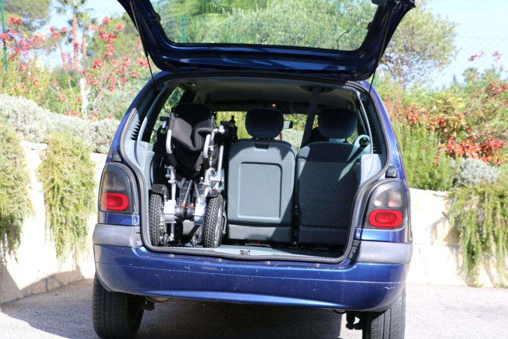 Eloflex X elektrisk rullestol lagt sammen i bagasjerommet på en bil. Bagasjerommet står åpent.