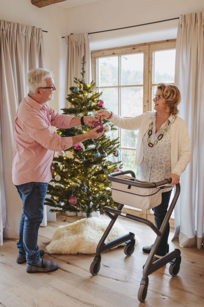Mann og kone pynter juletre og bruker Saljol Innomhus Rollator