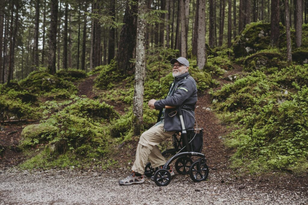 Mann sitter på Saljol Allrounder Rollator i skogen
