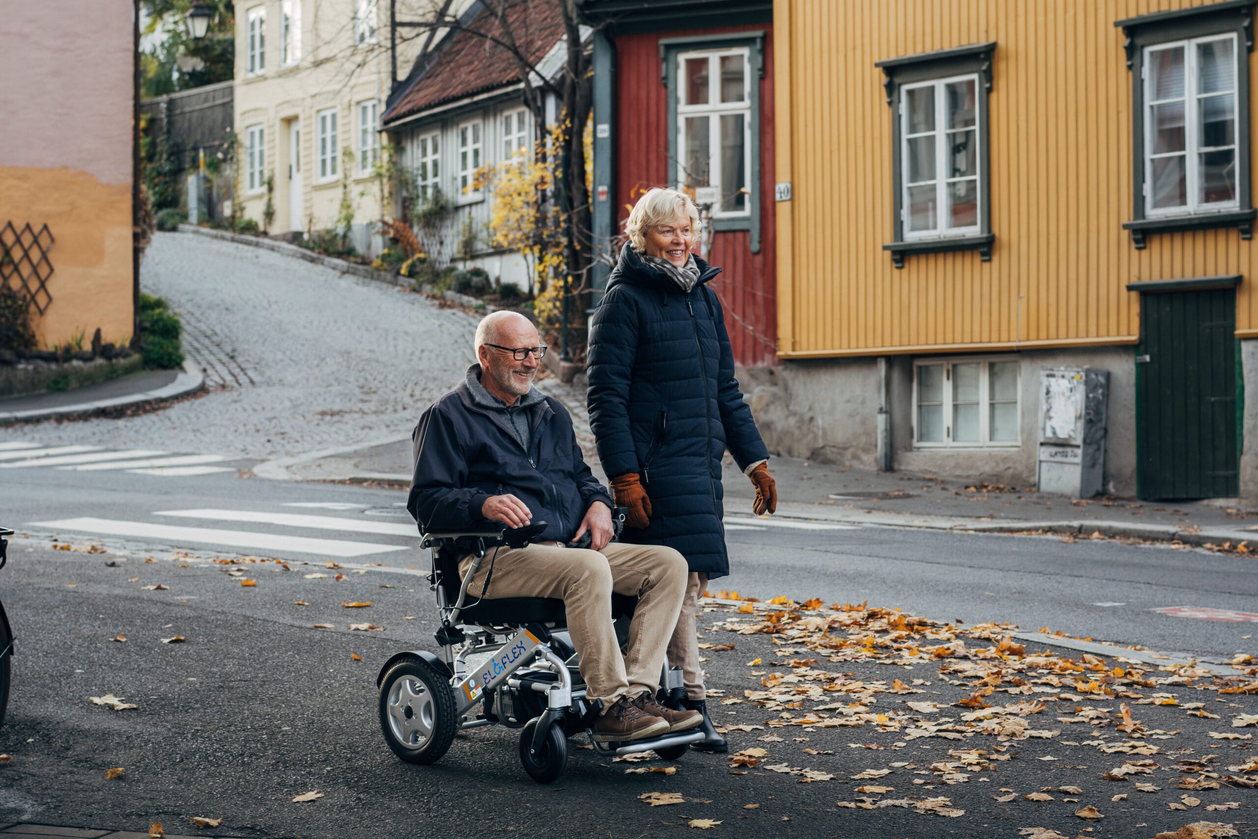 Äldre par på promenad. Mannen sitter i en Eloflex elektrisk rullstol.