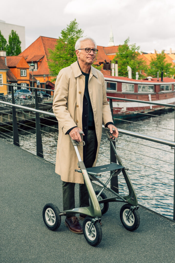 Mann med rollator på promenad i staden