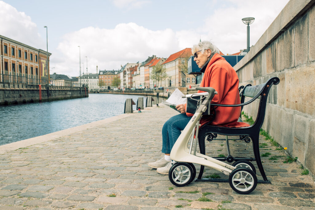 Dame sitter på benk med byACRE rollator på siden